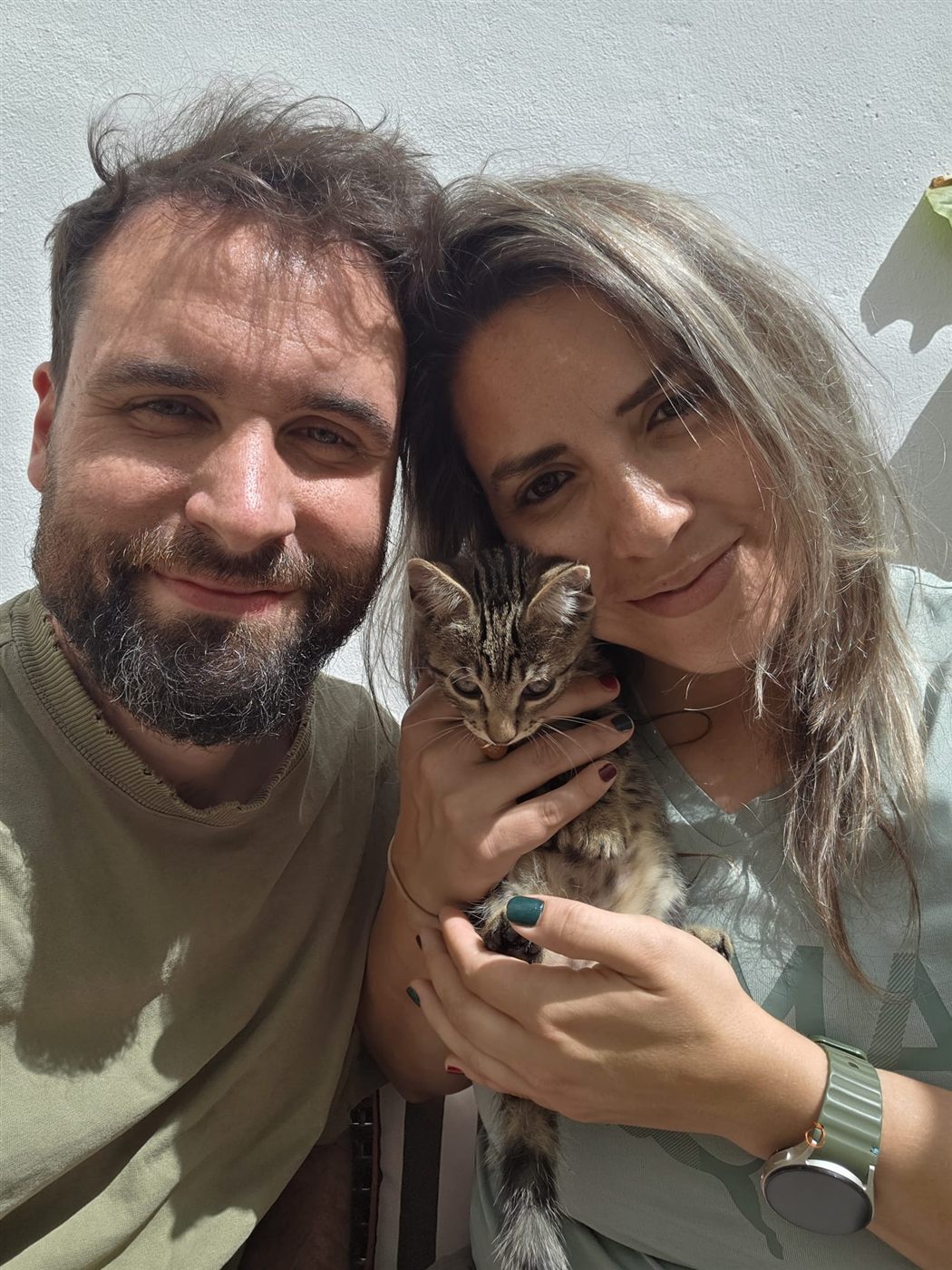 Austin and Michelle smiling, with Michelle holding Cashew, a young tabby cat