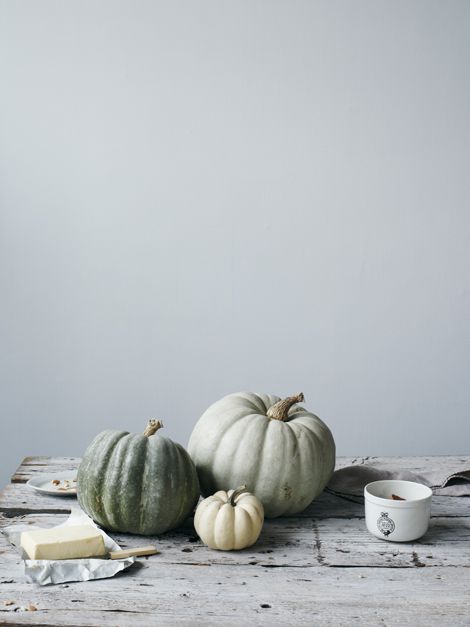 Gray-green and white pumpkins on an old wood table with butter and a little pot