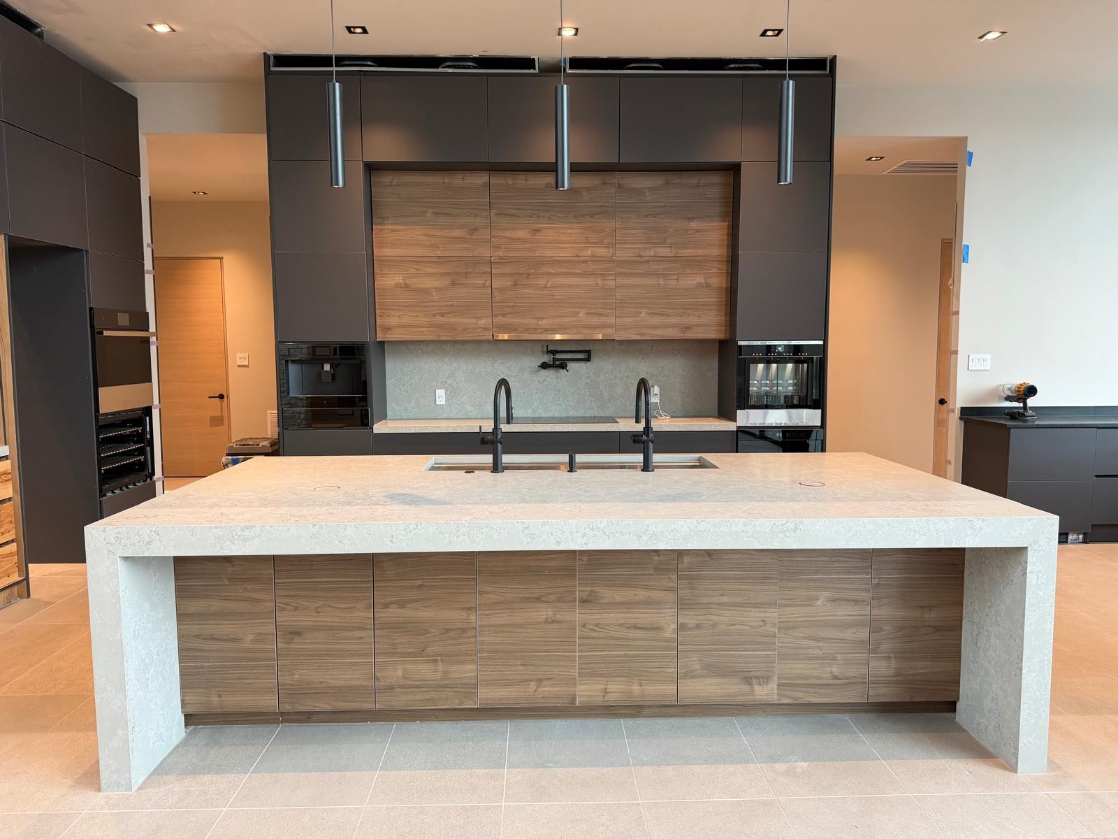 Mannapov kitchen as built: the same dark cabinetry, timber panel and stone island